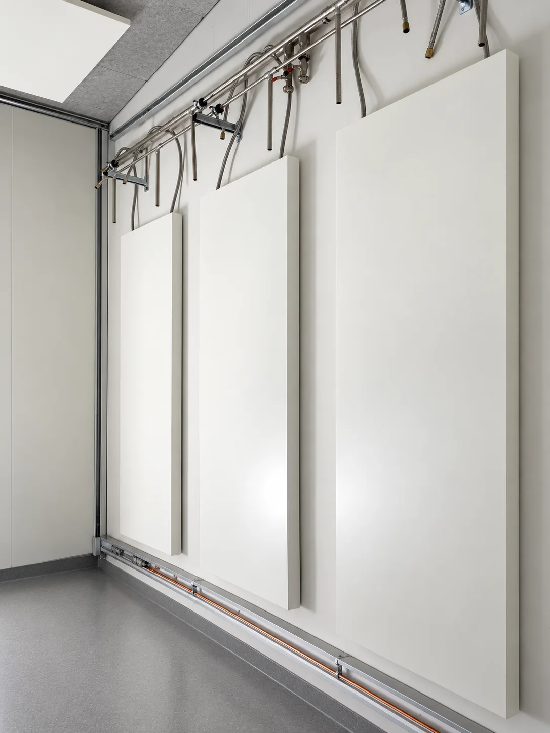 Detailansicht vertikaler Wandmodule mit darüberliegenden Rohrleitungen und flexiblen Anschlüssen